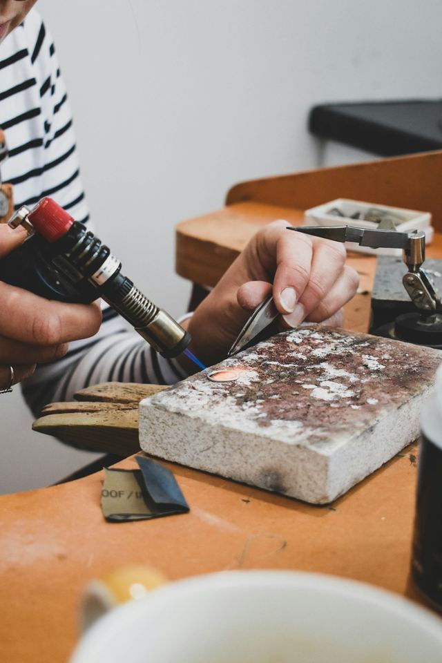 Manos de un orfebre trabajando una pieza en el taller